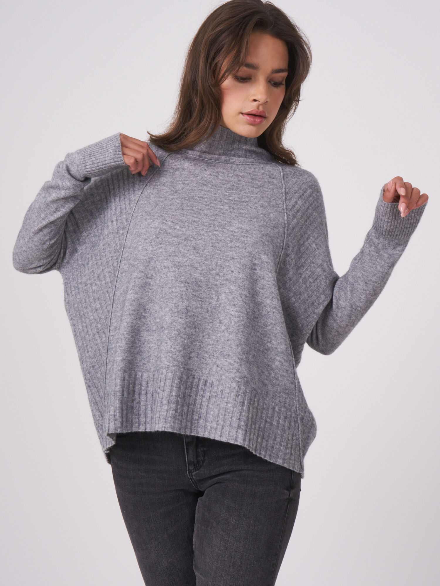 Oversized poncho-trui met geribde structuur en knooplijst aan de achterkant.